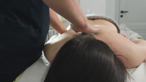 bodywork therapist rubbing back of female guest with fingertips on massage bed in calm spa environment under soft lighting conveying professional treatment and soothing relaxation experience
