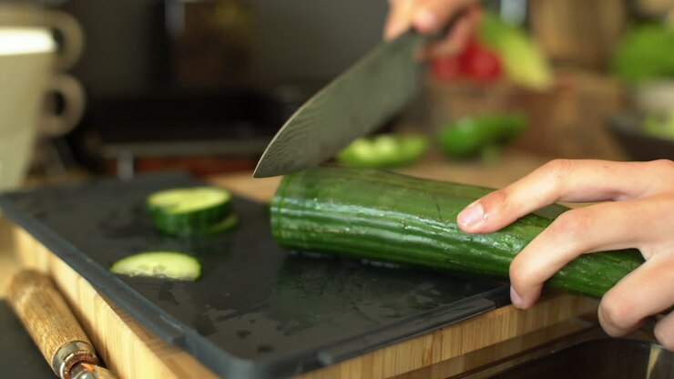 Close Up of Female Hands Slicing a Cucumber