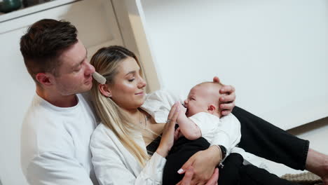 caring caucasian man embracing his wife holding their newborn. happy family portrait.