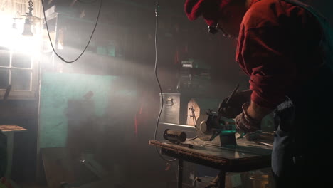 worker sharpens tool on bench grinder