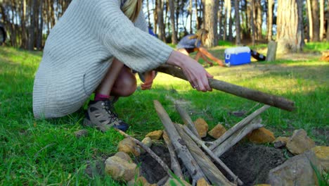 mujer preparando una fogata en el bosque en un día soleado 4k