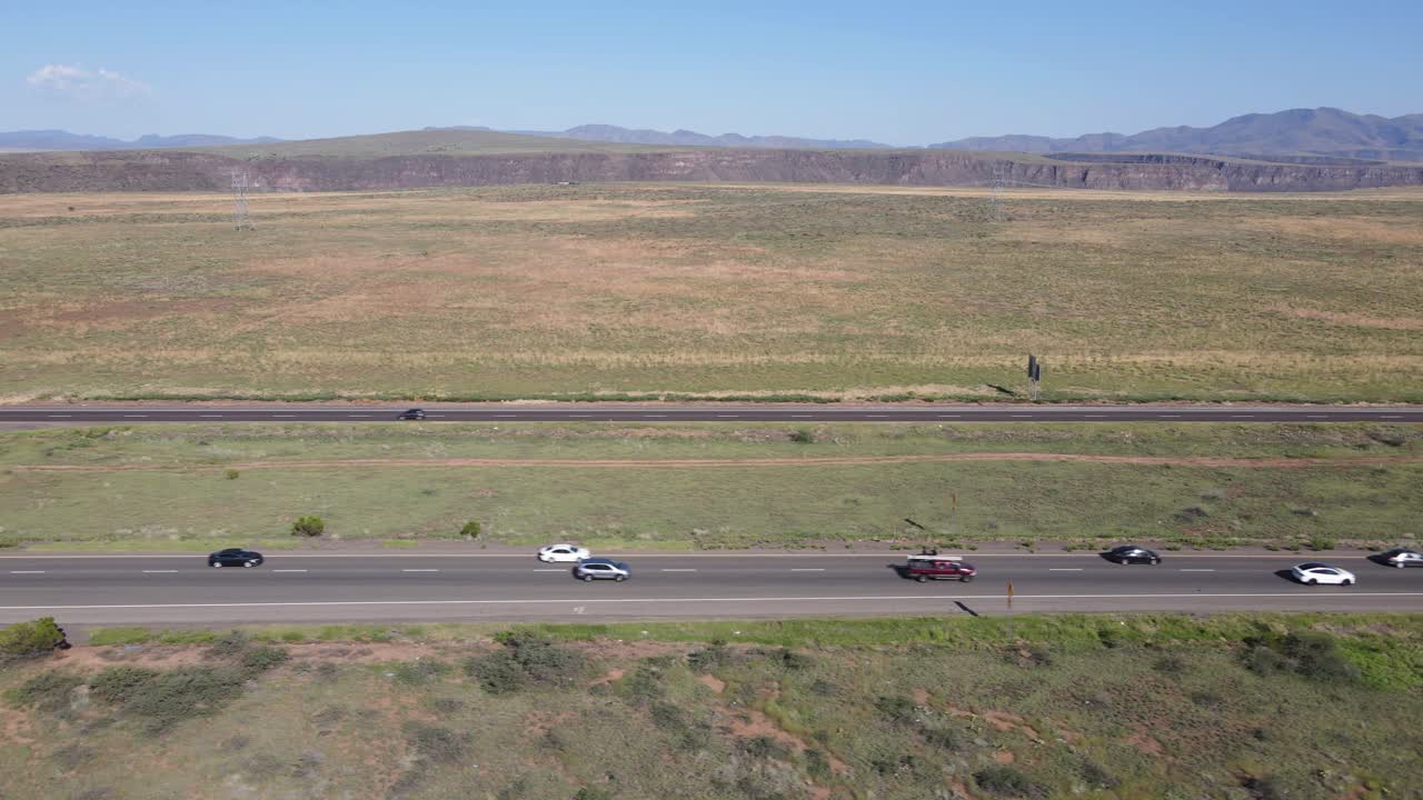 번잡한 교통과 푸른 하늘과 초원을 배경으로 보여주는 고속도로 옆을 따라 날아가는 드론