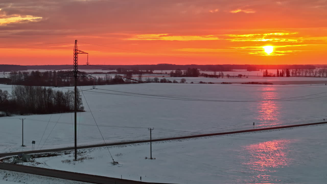 Flying over a frozen winter landscape under an orange colored sky during sunrise