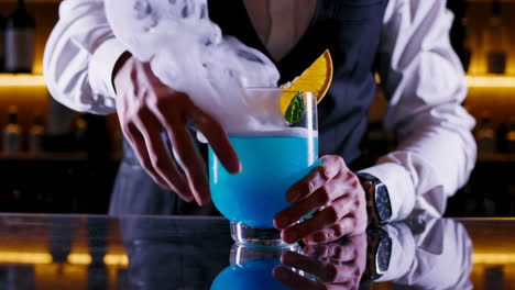 bartender preparing a blue cocktail with smoke