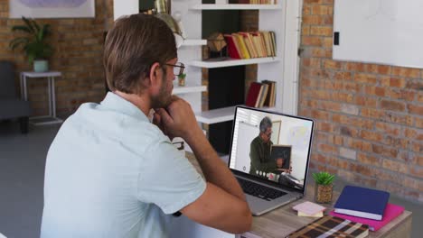 estudiante caucásico usando una computadora portátil en una videollamada con un profesor masculino
