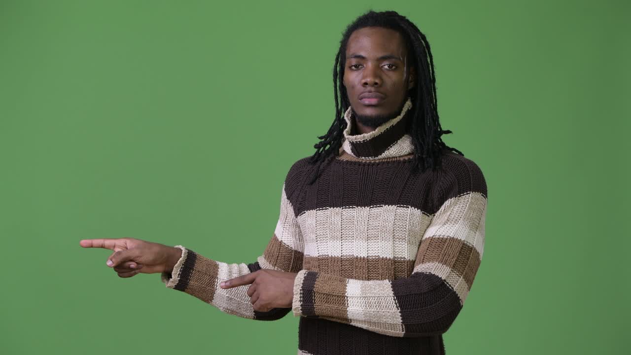 Young handsome African man with dreadlocks against green background
