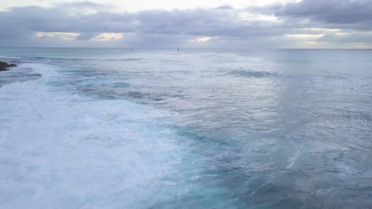 olas azules brillantes y espuma de mar blanca chocando contra una costa rocosa en el oeste de oahu honolulu koolina hawaii con veleros en el fondo de la puesta de sol, muñeca aérea