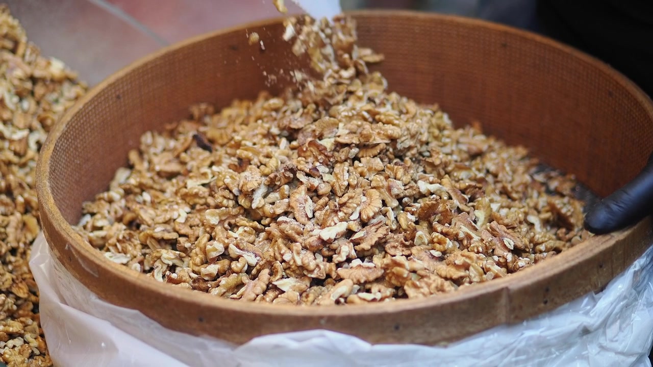 Fresh Shelled Walnuts Being Poured Into a Wooden Basket
