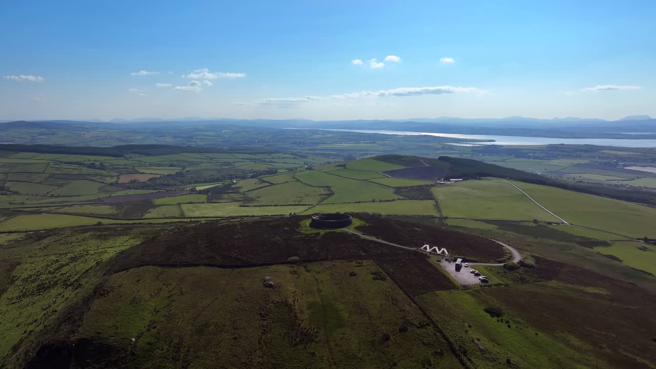 Grianan of Aileach, County Donegal, Ireland, June 2023. Drone wide angle counter clockwise orbit above the iconic Gaelic Ringfort surrounded by green fields with Drongawn Lough in the background.