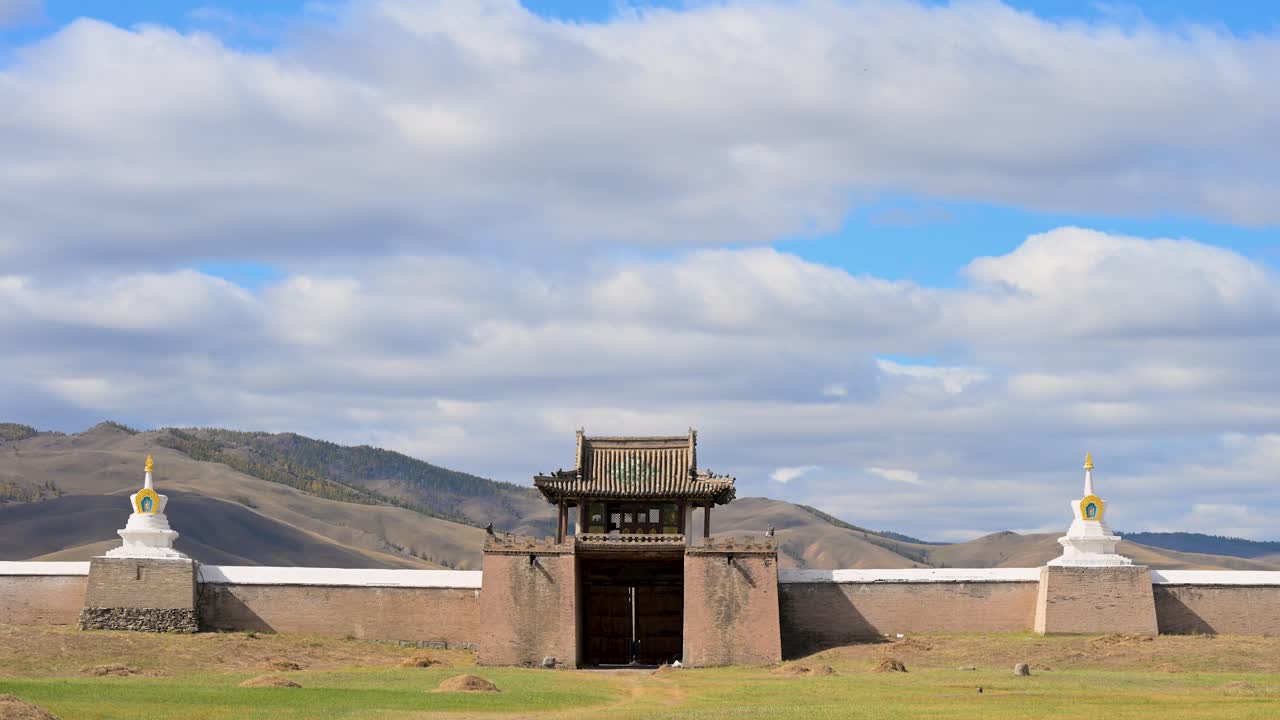 Laaja kuvakulma portista ja valkoisesta stupamuurista, joka ympäröi Erdene Zuuta Kharkhorinissa, Mongoliassa. Muinainen buddhalainen temppelikokonaisuus nähtynä ruohoiselta arolla.