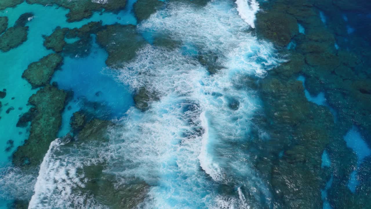 파도가 부서지는 푸른 석호 암초의 공중 드론 샷으로 암초의 자연미와 평화로운 분위기를 강조