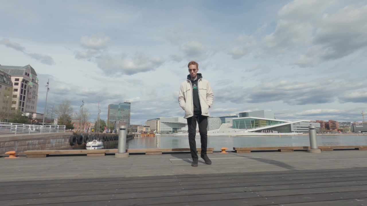 Persona che cammina lungo la passeggiata sul lungomare di Oslo con lo skyline moderno della città sullo sfondo