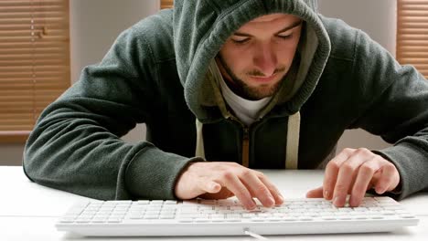 hombre con capucha y trabajando en la computadora