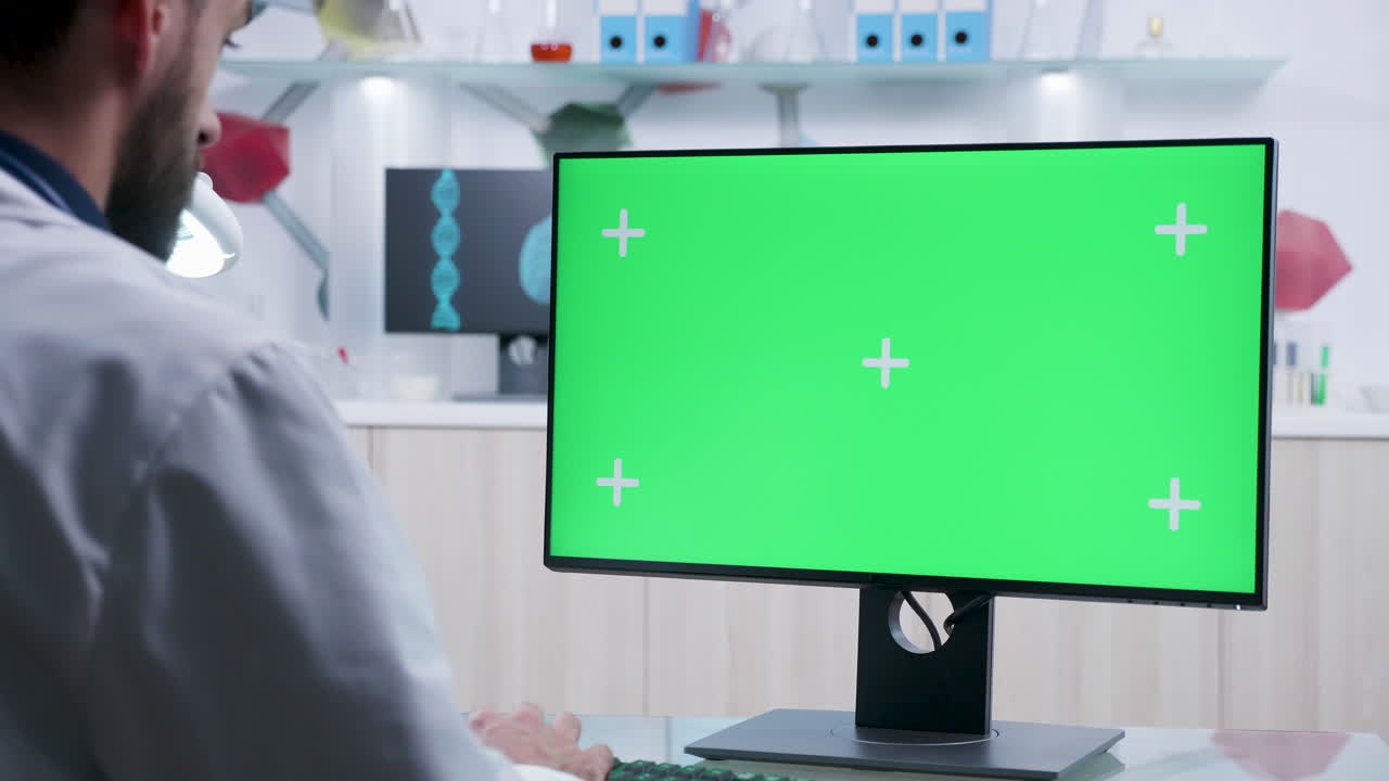 Scientist working with a green screen computer in a lab