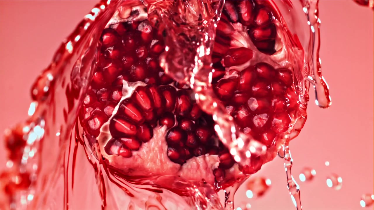Vand sprøjter på et halveret granatæble i slowmotion