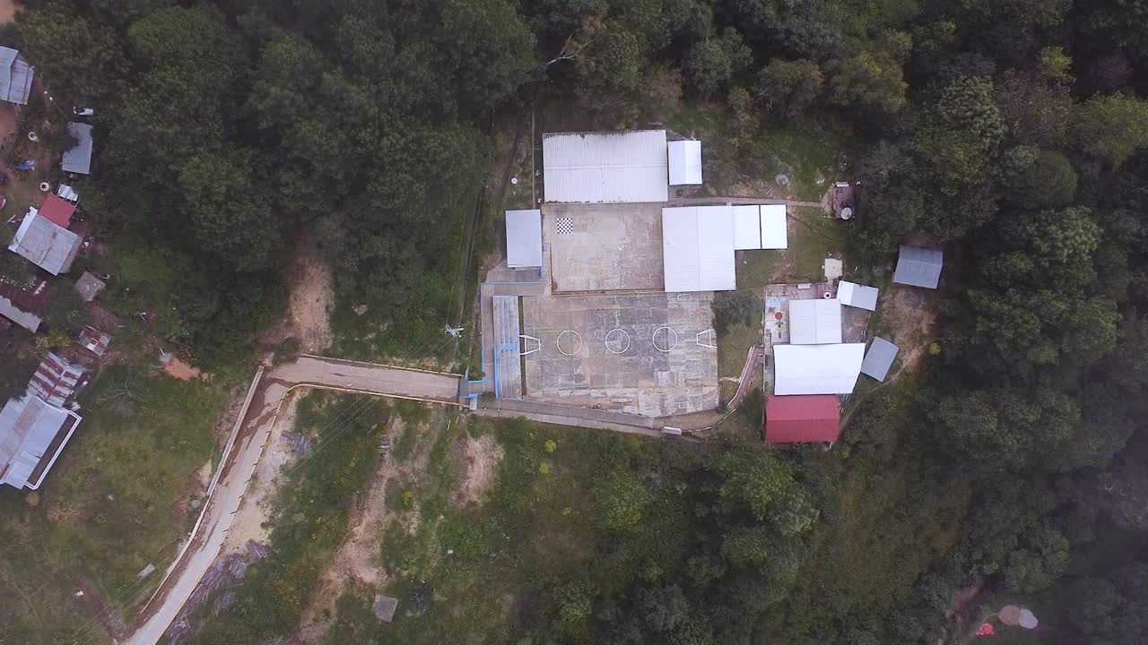 vuelo de avión no tripulado sobre una escuela rural rodeada de bosque en oaxaca, méxico