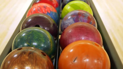 row of ten pin bowling balls lined up in a rack