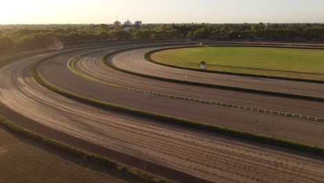 Vuelo-Aéreo-Hacia-Adelante-Sobre-El-Hipódromo-Vacío-Durante-La-Puesta-De-Sol-Dorada-En-Buenos-Aires,-Argentina---Rodeado-De-Bosques-Verdes