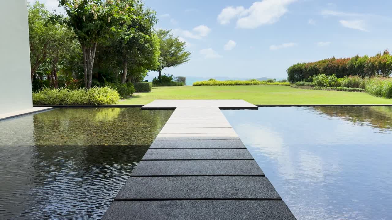 En fredfyldt gangbro over vand ved et luksusresort i Phuket, Thailand, med frodigt grønt og moderne design.