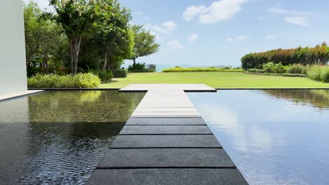 a serene walkway over water at a luxury resort in phuket, thailand, showcasing lush greenery and modern design