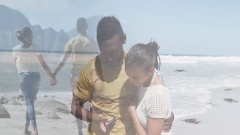 compuesto de una feliz pareja afroamericana usando un teléfono inteligente, y caminando de la mano en la playa