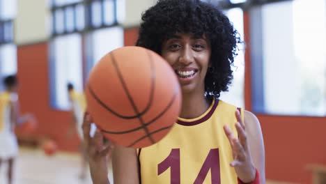 retrato de una jugadora de baloncesto afroamericana sosteniendo la pelota en una cancha cubierta, en cámara lenta