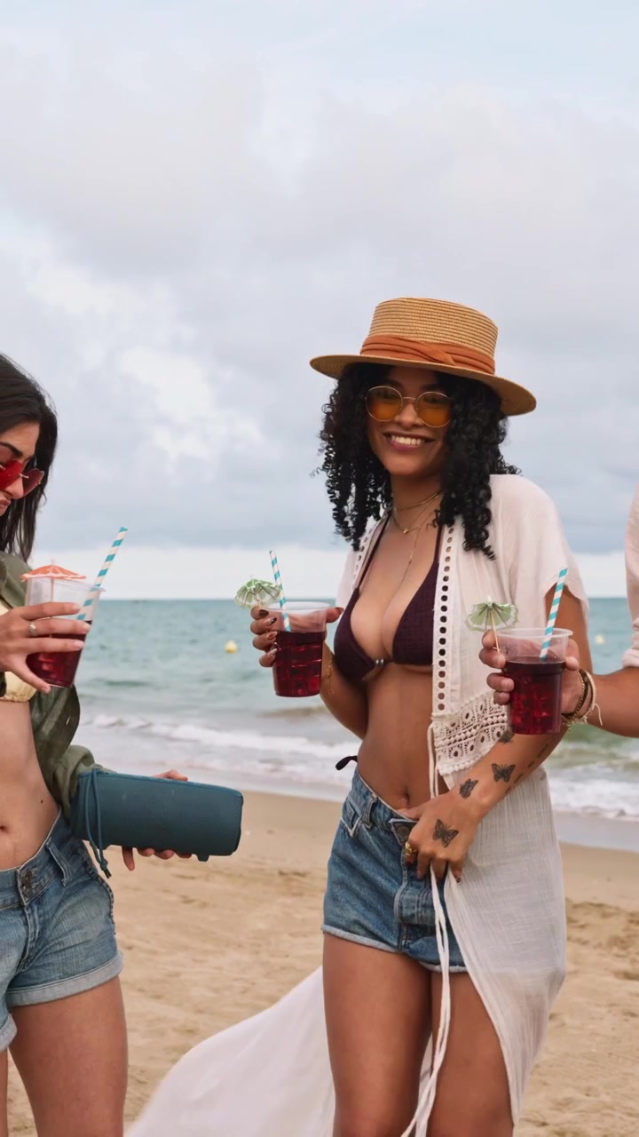Gruppo di amici che ballano e bevono cocktail in spiaggia