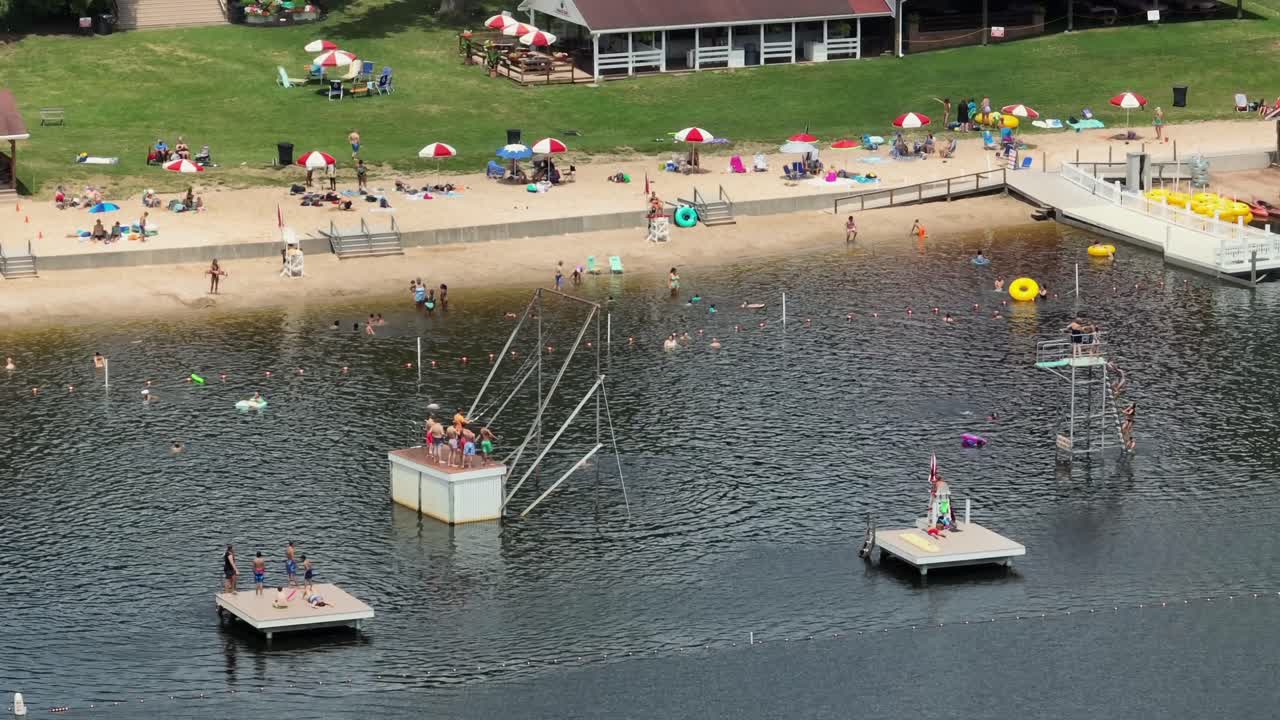 Aerial zoom shot kids and families playing in lake with sandy beach in Mount Gretna, PA, USA. Hot summer day in america.
