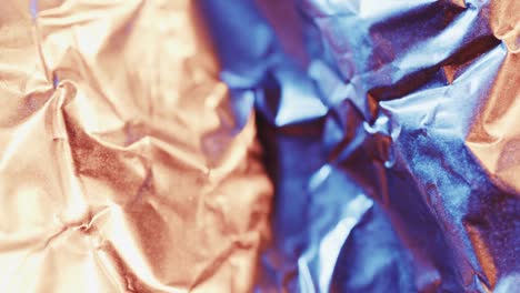 close up of blue and beige crumpled pieces of paper in slow motion