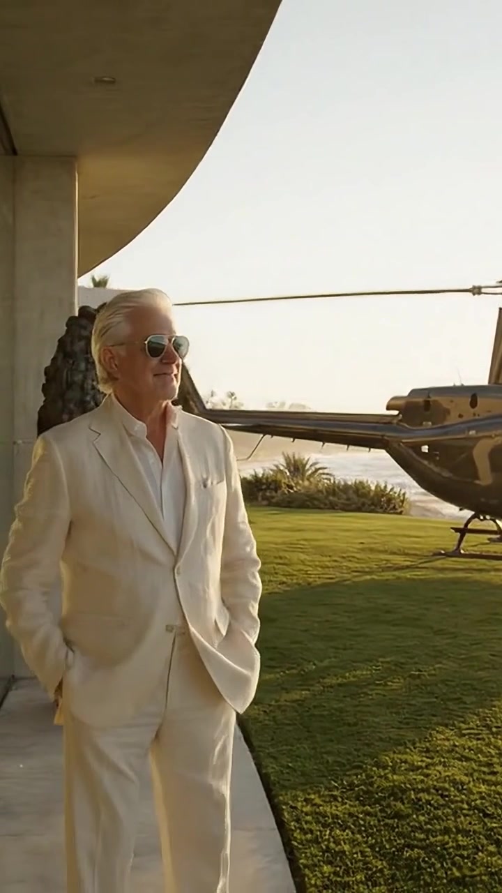 Uomo elegante in abito di stile sta casualmente vicino a un elicottero su uno splendido paesaggio al tramonto, emanando lusso e raffinatezza in un ambiente di lusso.