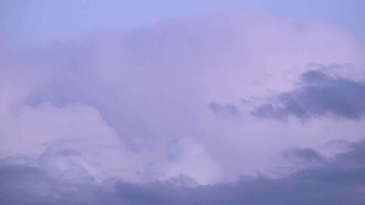 A time lapse of billowing purple and pink Cumulous Nimbus and Cirrus clouds are pushed across the sky by the wind at sunset