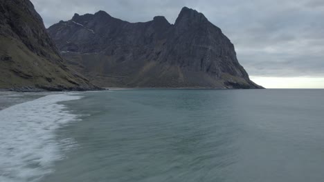 vista aérea sobre las olas en la playa de kvalvika, sombría tarde de otoño, en lofoten, noruega - reversa, disparo de drones