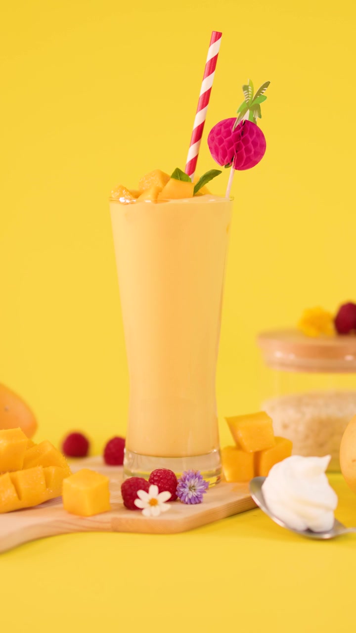 Smoothie rinfrescante al mango in un bicchiere su sfondo giallo
