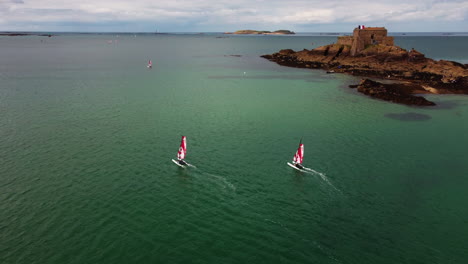 aerial view of catamaran boat race with fortress on petit be tidal island in background, france