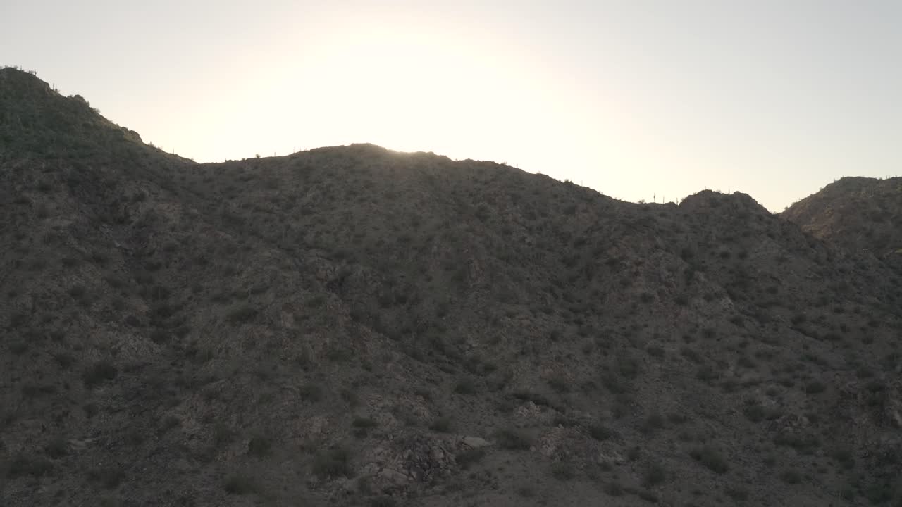 drone volando montaña abajo con puesta de sol detrás de él