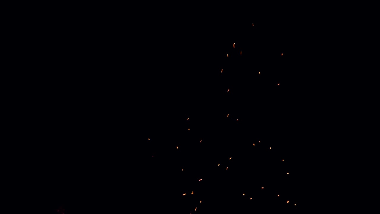 la noche negra está rota por brasas anaranjadas de un fuego que flota desde las llamas de abajo.