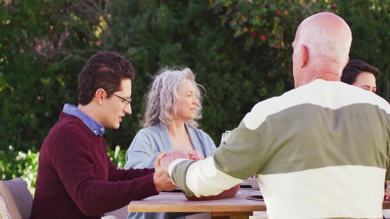 행복한 백인 가족이 정원에서 저녁 식사 전에 기도하고 있습니다.