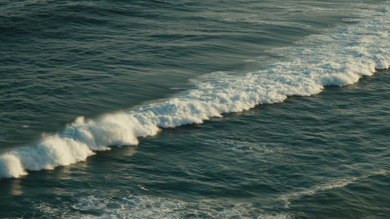 Waves moving towards the shoreline with sunset
