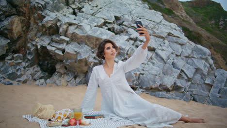 attractive lady taking smartphone selfie on sandy shore. romantic girl on picnic