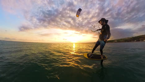 man practicing foil kitesurfing in beautiful sunset scenery. aerial tracking shot