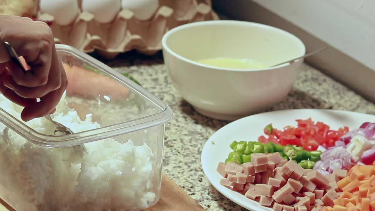 Fluffing up leftover rice as a step in cooking fried rice recipe showing a candid simple daily life