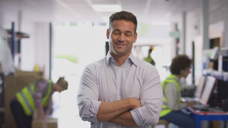 portrait of smiling male manager in busy logistics distribution warehouse