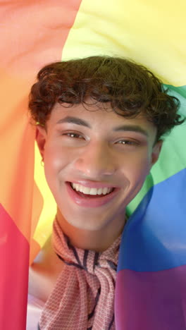 vertical video: smiling person wrapped in rainbow flag celebrating pride and diversity