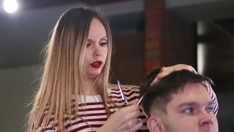 en gros plan, le maître coiffeur fait la coiffure et le style avec des ciseaux et un peigne. concept de salon de coiffure.