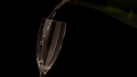 champagne pouring into flute on black background