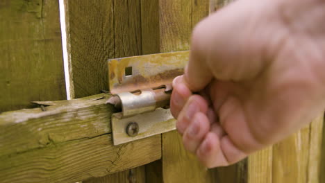 man closes gate and latches old sliding lock