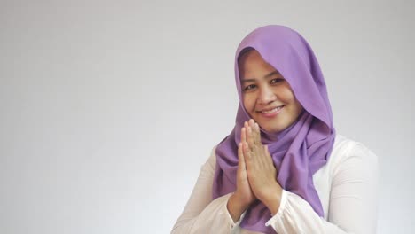 beautiful asian muslim lady smiling and shows greeting gesture, concept of islamic celebration of ramadan or eid fitr