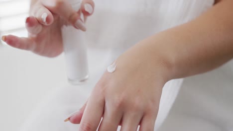 caucasian plus size woman with bathrobe putting cream on hand in slow motion