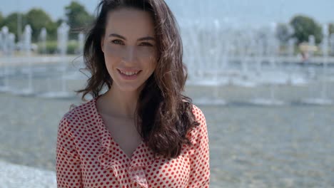 portrait of beautiful girl in colorful summer clothes sitting near a fountain