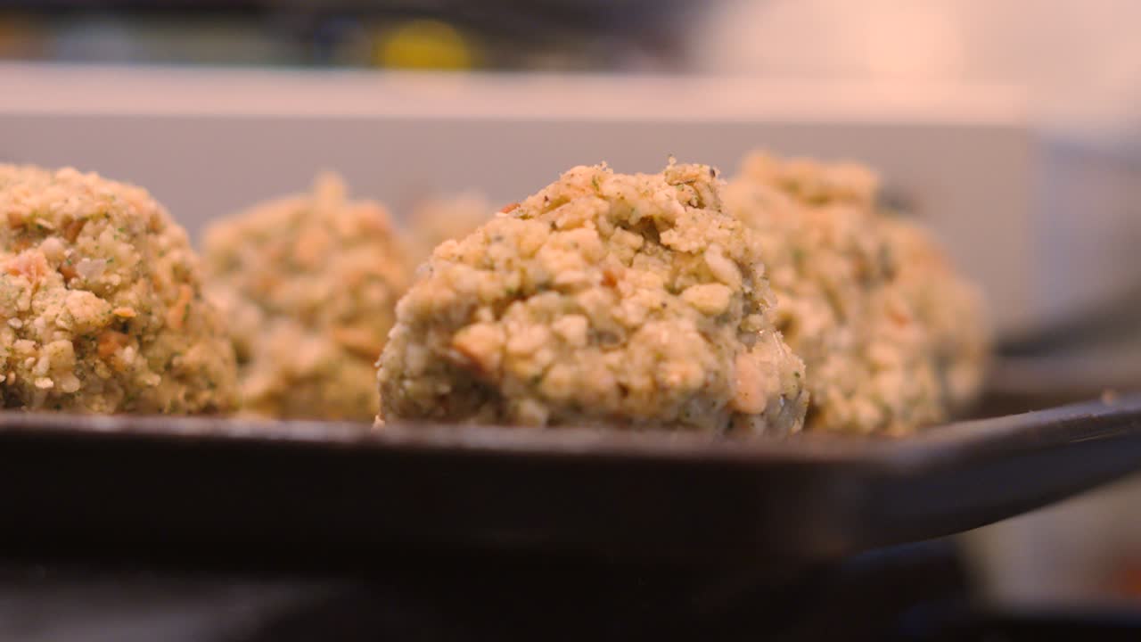 Slow Dolly Shot Towards Sage and Onion Stuffing Balls on Baking Tray Ready to Cook. Chef in Background Prepping Food. High-quality food cinematography for cooking content